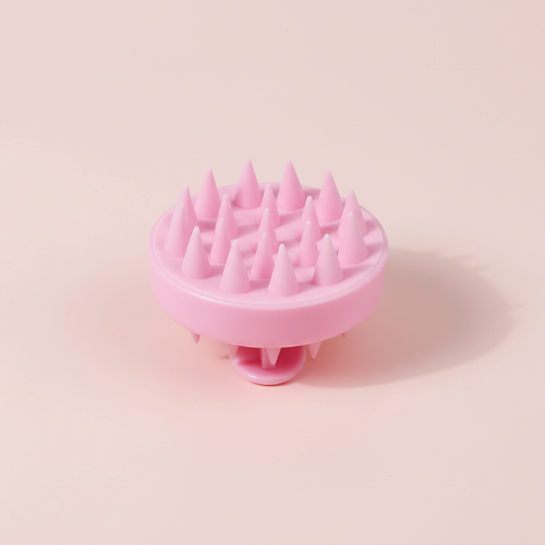 Brosse ronde rose en silicone présentée seule sur fond rose pâle